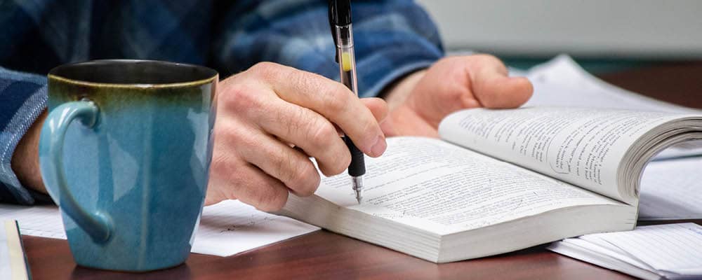 Student holding an open book reviewing highlighted text