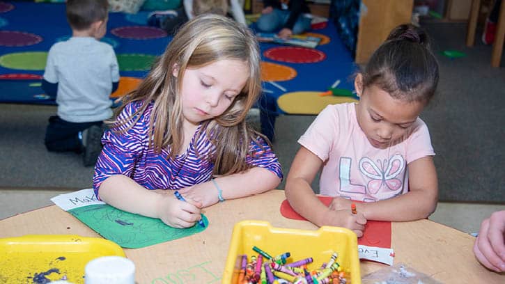 Two children coloring at a table together.