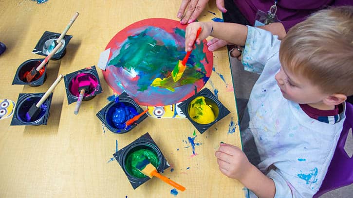 A child painting with sponge brushes.