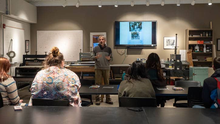 Professor presenting to students in the printmaking studio.